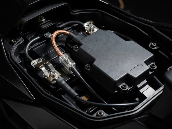 High-contrast close-up of motorcycle battery compartment showing clean SAE fused lead and solid-state power distribution box
